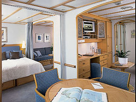 The Commodore Club, or double staterooms, feature a full 395 square feet with two entire bathrooms, two full closet as well as two entertainment centers and couches. They may be configured as shown here with the full table or with both beds down. The option for the beds include two doubles or one double with two single beds.